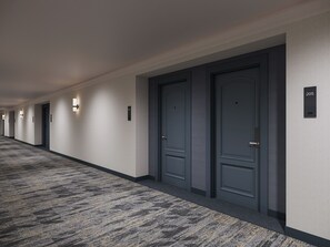 A hotel corridor with doors, numbered signs, and wall-mounted light fixtures. - Pomeroy Inn & Suites Hotel Dawson Creek (Dawson Creek)