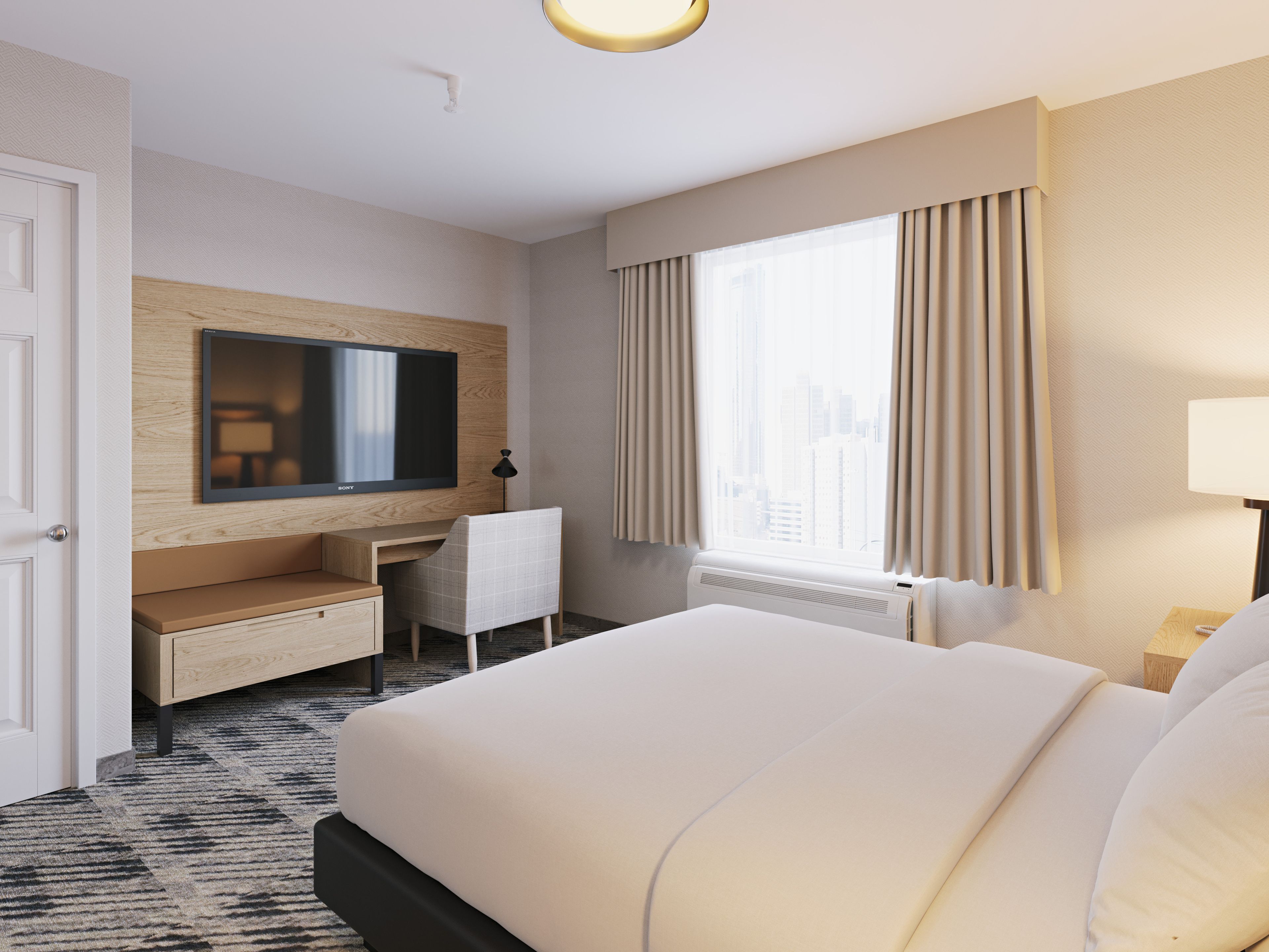 A hotel room with a large bed, a desk, a flat-screen TV, and a window with curtains.