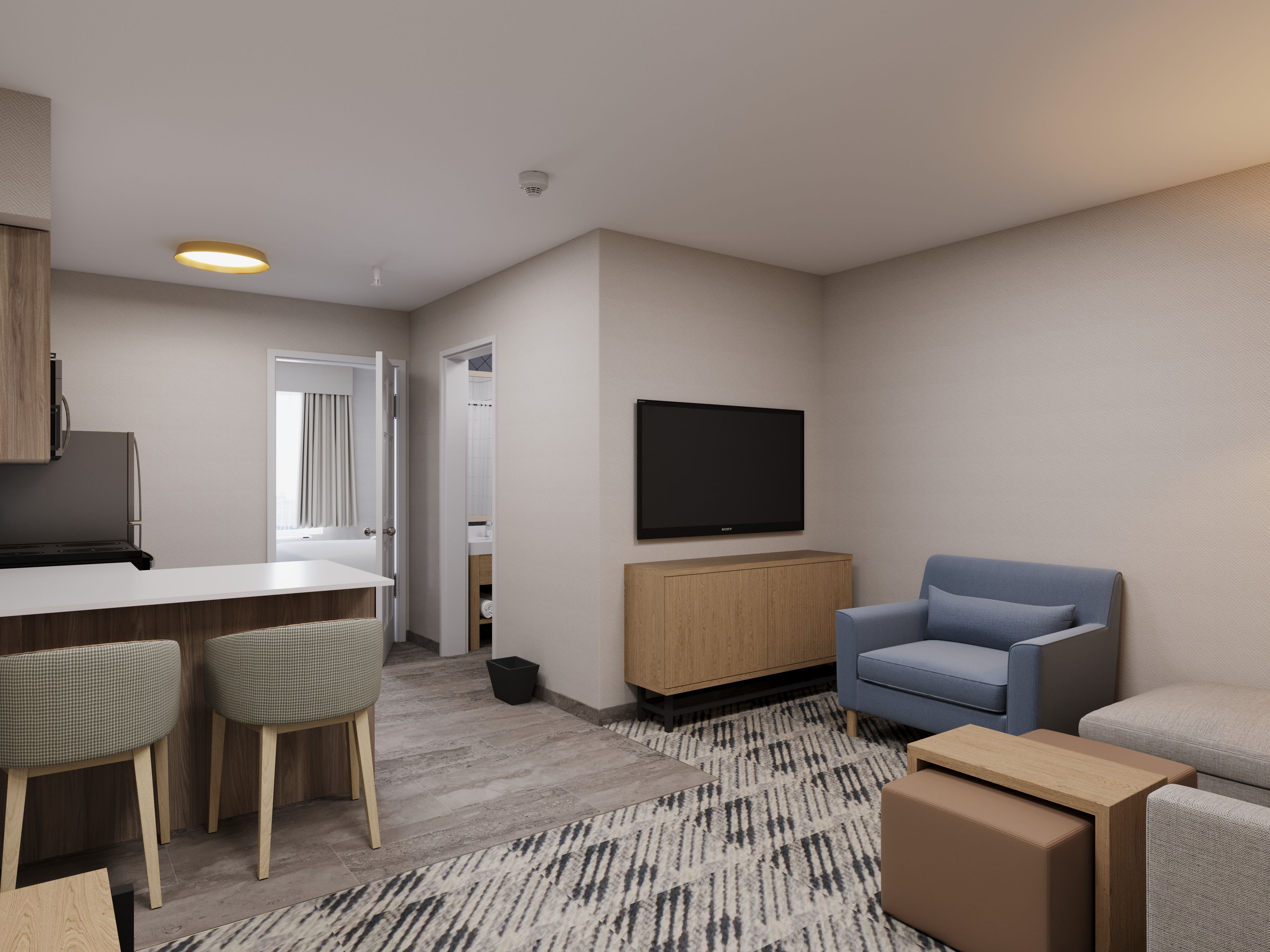 A modern living room with a flat-screen TV, a blue armchair, a sofa, and a kitchen area with a bar.