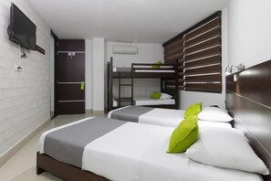 A hotel room with two beds, a TV mounted on the wall, a door, and a window with blinds.