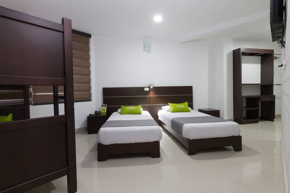A hotel room with two beds, a nightstand, and a wardrobe.