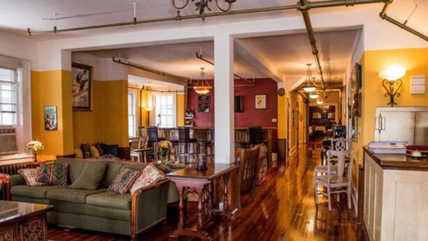 Ein geräumiges Wohnzimmer mit einem grünen Sofa, einem Holztisch und einem Essbereich mit Stühlen und Tisch.