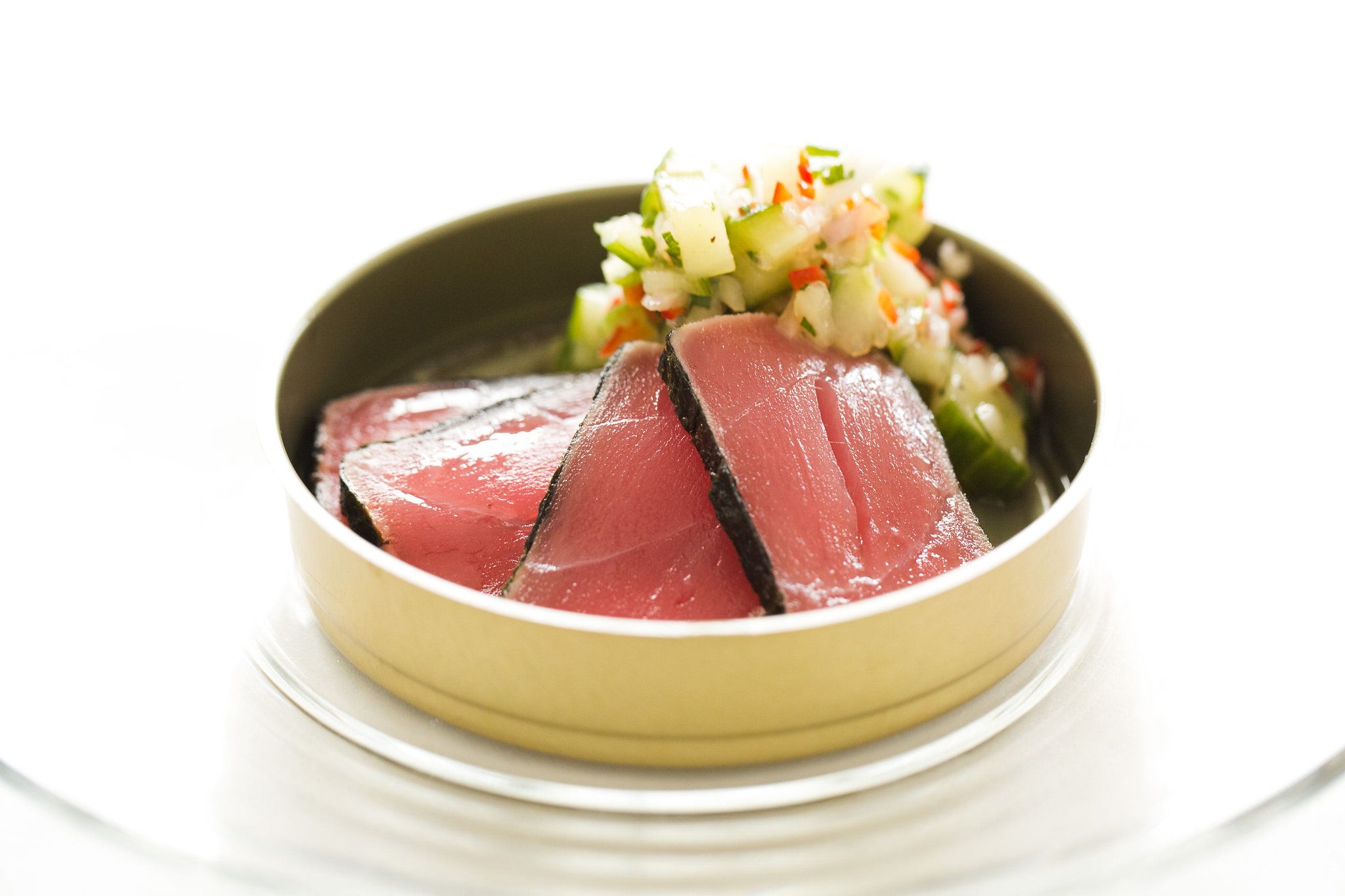 A bowl of sliced meat with a side of diced vegetables.