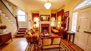 A traditional living room with a fireplace, a staircase, and a bookshelf. - Bay Haven Inn of Cape Charles (Cape Charles)