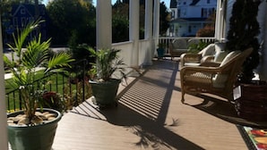 A covered porch with potted plants, wicker furniture, and a view of the neighborhood. - Bay Haven Inn of Cape Charles (Cape Charles)