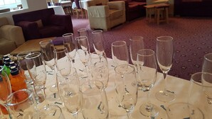 Rebost d'hotel amb una taula preparada per a un esdeveniment formal, amb múltiples vasos i ampolles de vi.