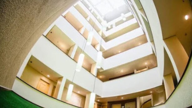 Ein mehrgeschossiges Interieur mit einem zentralen Atrium, mehreren Stockwerken und einem geschwungenen Deckenstil.