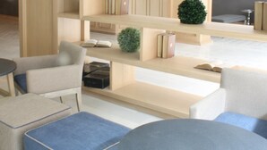 A modern library with bookshelves, seating areas, and a small table. - Hotel Plaza Revolución (Mexico City)