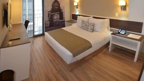 A hotel room with a bed, bedside tables, a desk, a chair, and a wall with a poster. - Hotel Plaza Revolución (Mexico City)