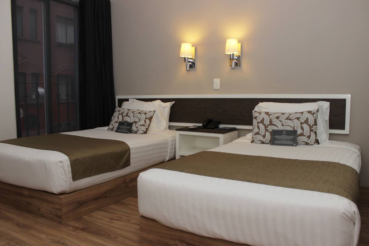 A hotel room with two beds, wooden headboards, and bedside tables.
