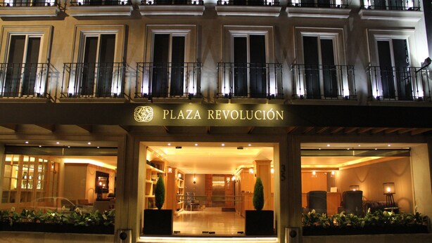 The exterior of Plaza Revolucion hotel with a well-lit entrance, large windows, and a sign above the entrance. - Hotel Plaza Revolución (Mexico City)