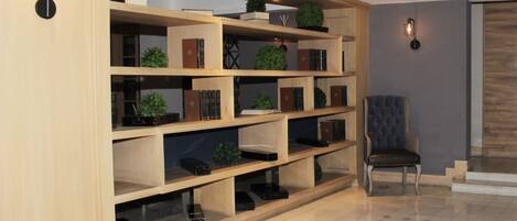 Een ruime kamer met een grote houten boekenkast, een comfortabele fauteuil en een betegelde vloer.