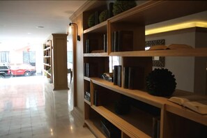 A hotel lobby with a large wooden bookshelf, a car parked outside, and a clean tiled floor. - Hotel Plaza Revolución (Mexico City)