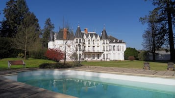 Una piscina al aire libre, sillones reclinables de piscina