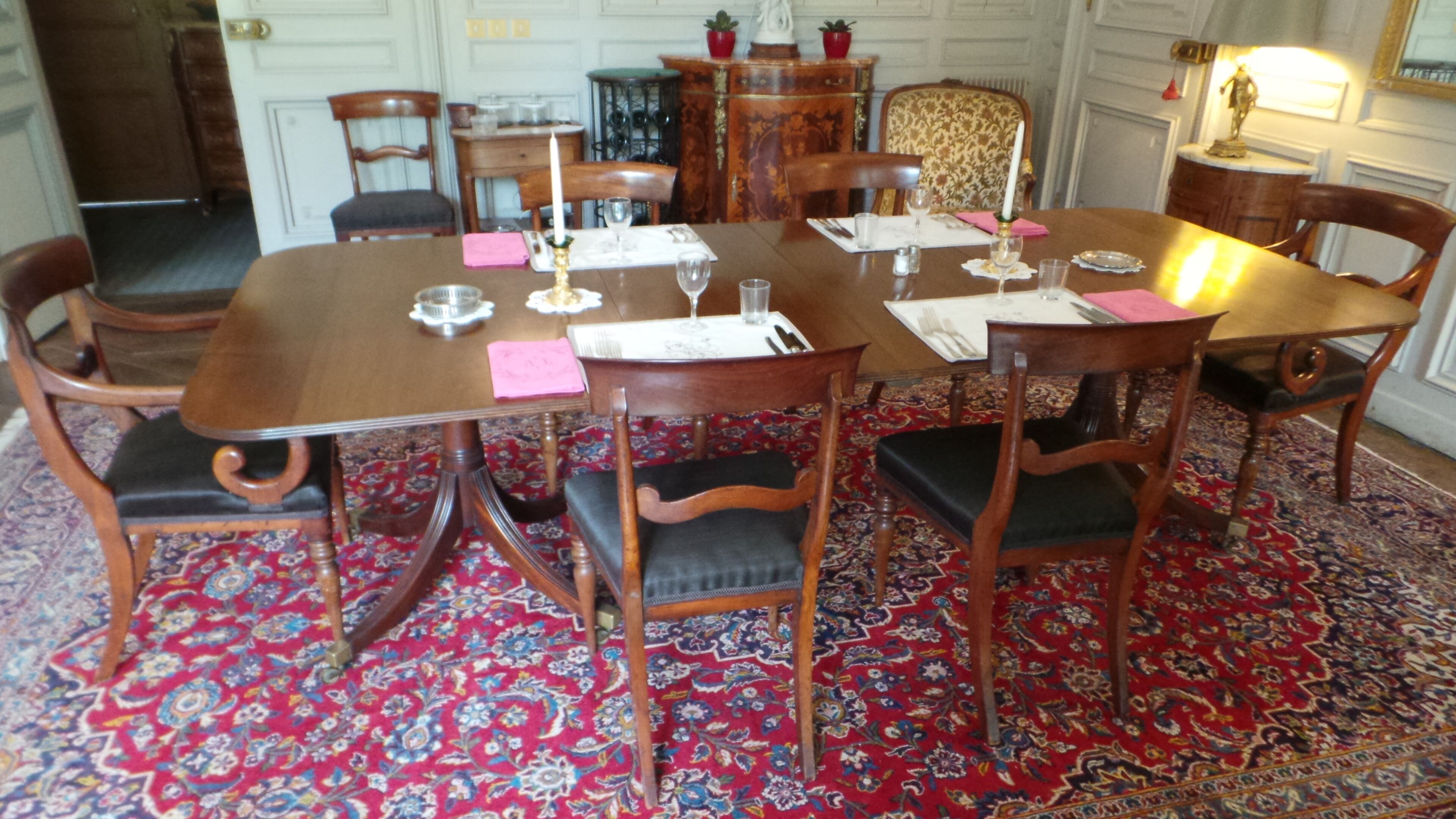 Ein Esszimmer mit Holztisch, gedeckt für vier Personen, umgeben von Stühlen mit gepolsterten Sitzflächen.