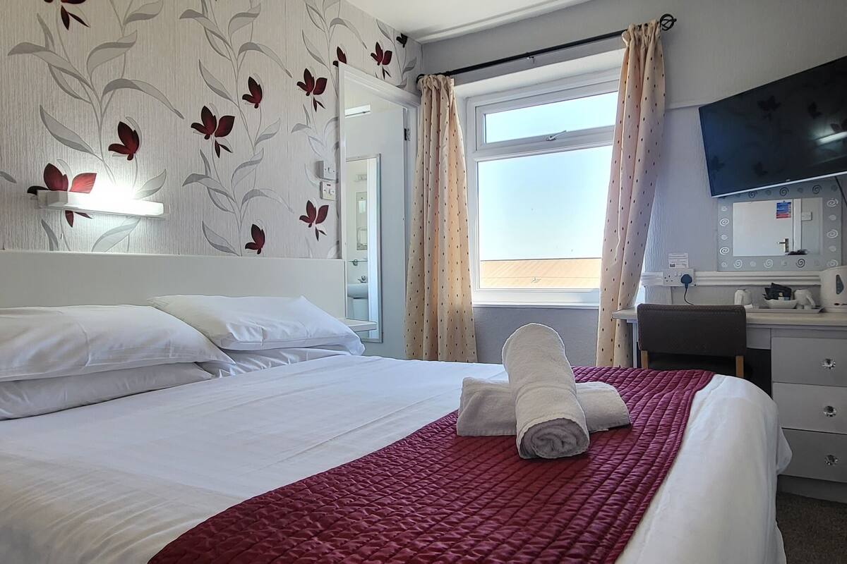 Een hotelkamer met een bed, een kaptafel met spiegel en een televisie aan de muur.