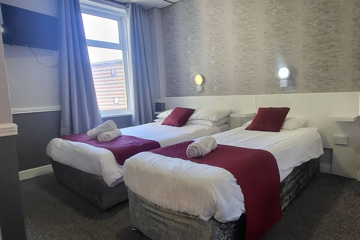 Een hotelkamer met twee bedden, een stoel en een radiator.