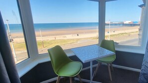A room with a view of the beach, a table, and two chairs. - Blenheim Mount Hotel (Blackpool)