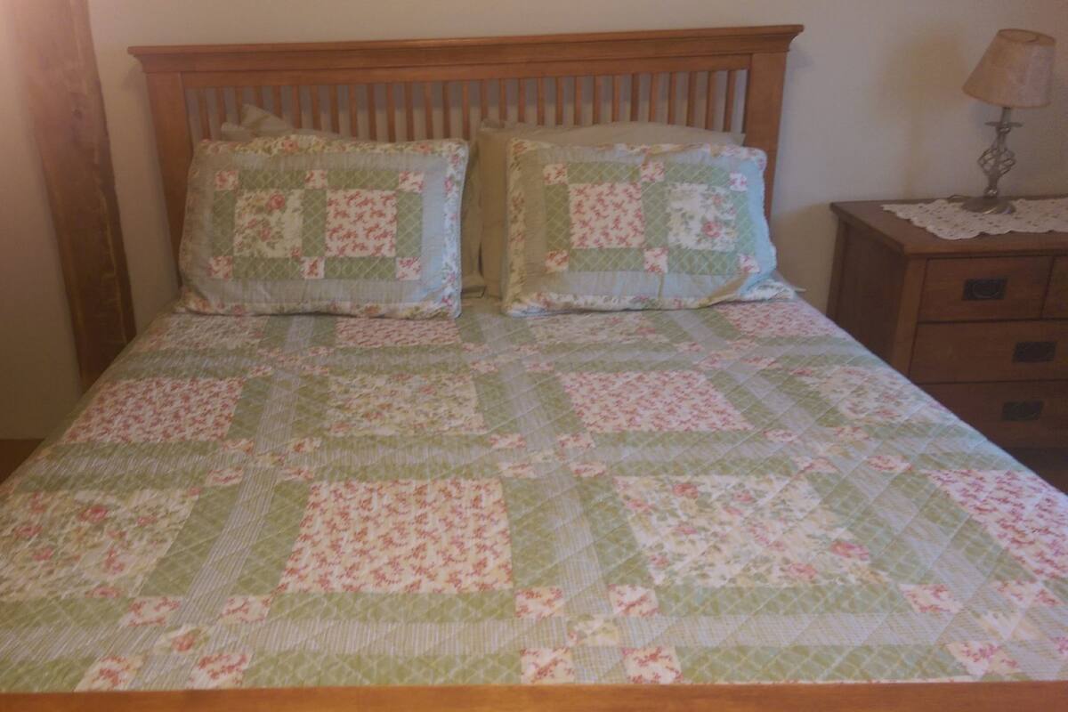 A bed with a floral quilt, wooden headboard, and two matching pillows.
