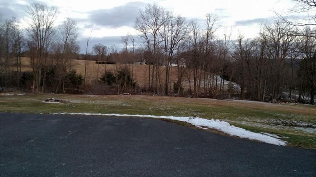 A parking lot with snow patches and leafless trees in the background.