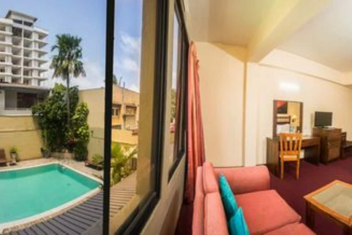 A hotel room with a pool view, a red sofa, a bed, and a desk.