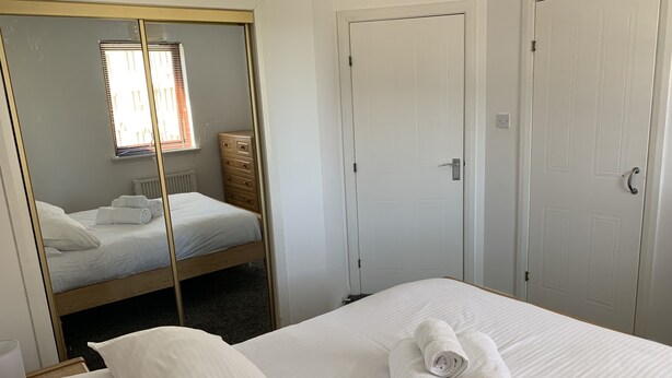 Une chambre à coucher avec un lit, une commode et deux portes.