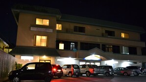 A multi-story hotel with several parked cars in front. - West Plaza Hotel Desekel (Koror)