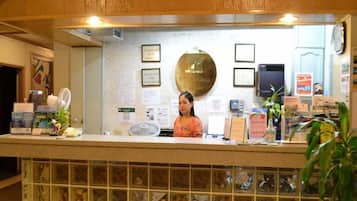 A reception desk with a woman behind it, a clock, and various informational signs.