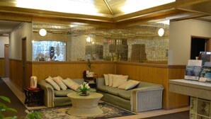 A lobby with a green sofa, a round coffee table, and a reception desk. - West Plaza Hotel Desekel (Koror)