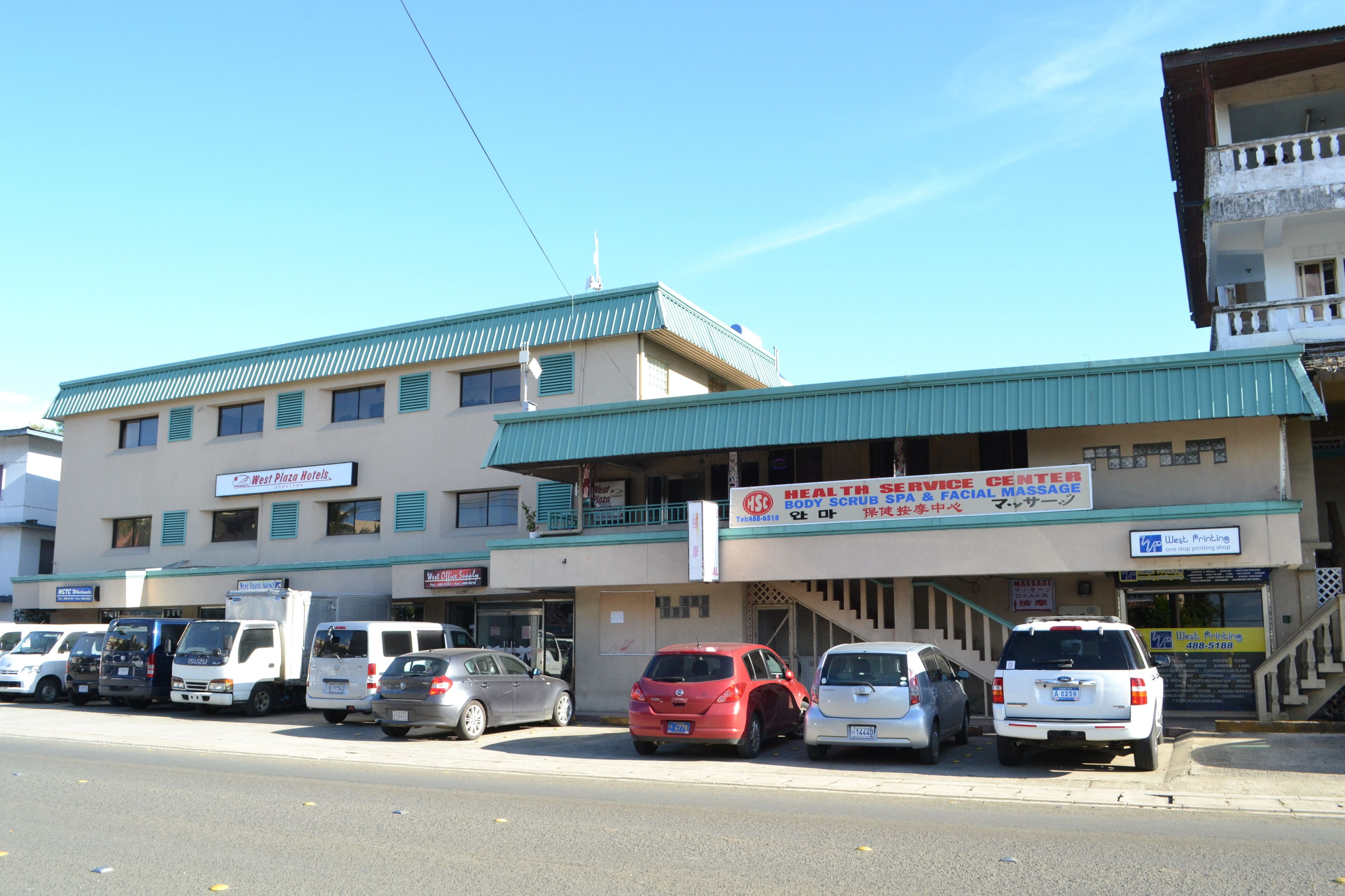 Un edificio con un letrero para un centro de servicios de salud y un estacionamiento con varios autos.