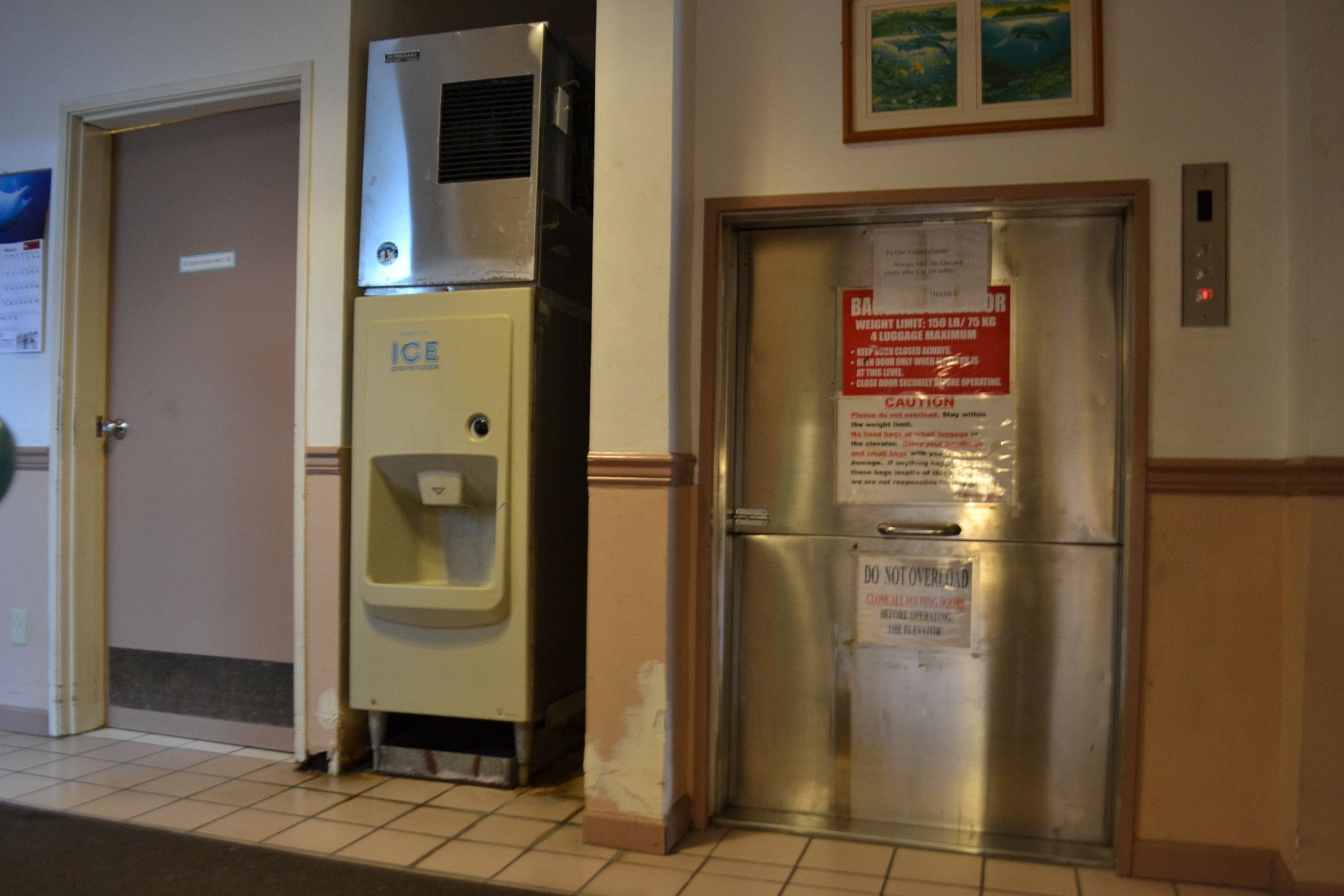 A restroom with a hand dryer, a water fountain, and a refrigerator.