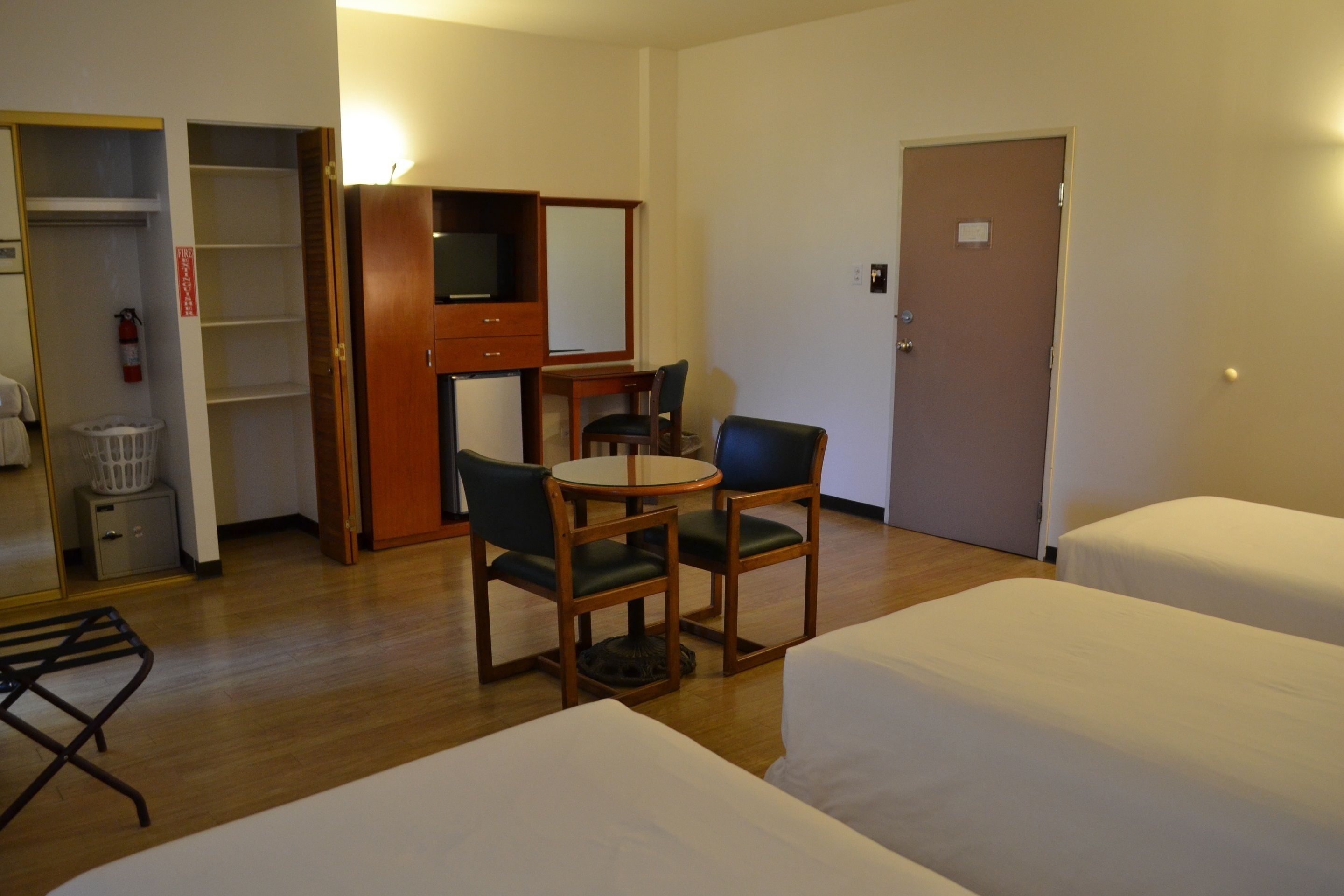A hotel room with two beds, a desk with a chair, a television, and a wardrobe.