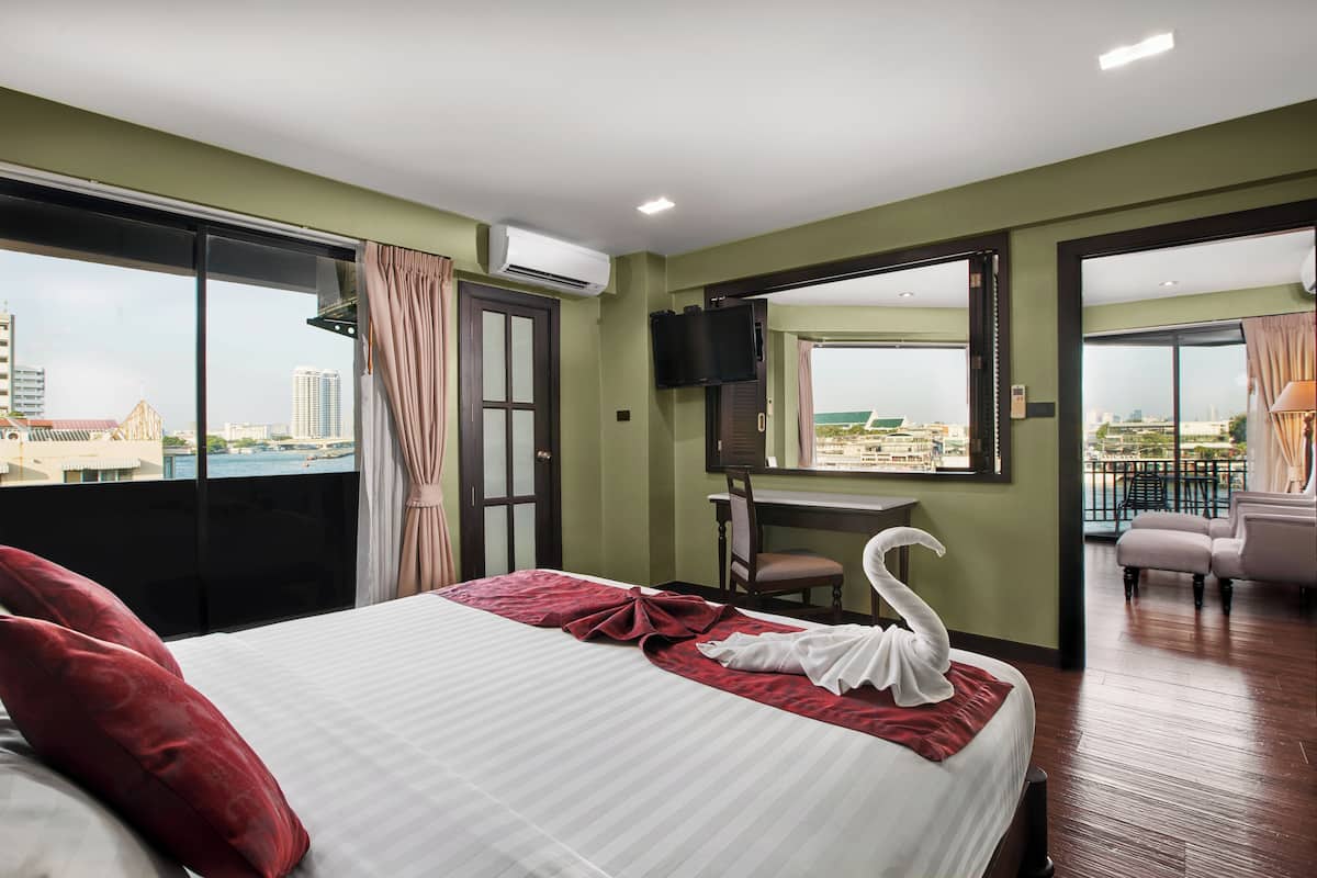 Quarto de hotel com cama, escrivaninha, cadeira, televisão e varanda com vista para a cidade.