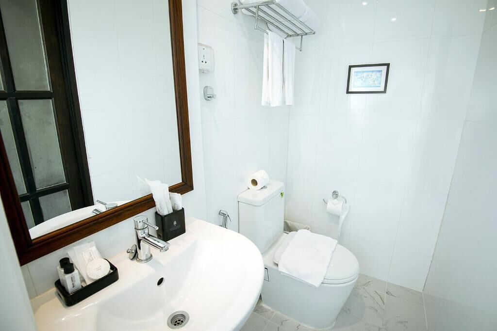 Un baño moderno con un lavamanos blanco, un espejo, un inodoro y un perchero para toallas.