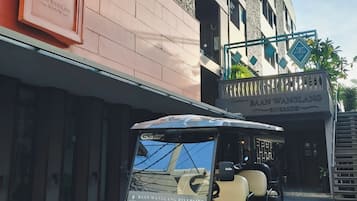 A golf cart parked in front of a building with a sign reading 'BAAN WANGLANG RIVERSIDE.'