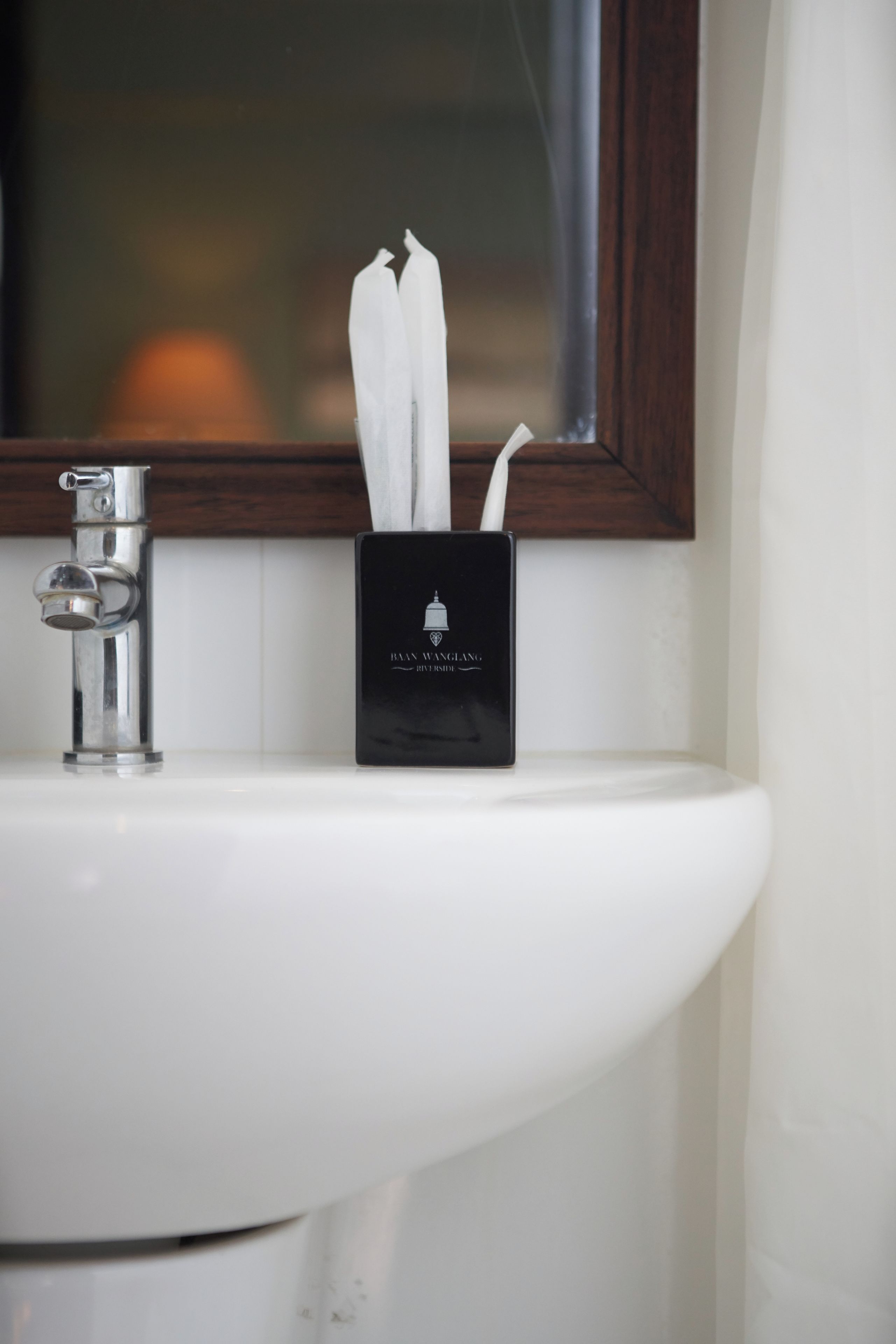A bathroom sink with a faucet and a black container holding white towels.