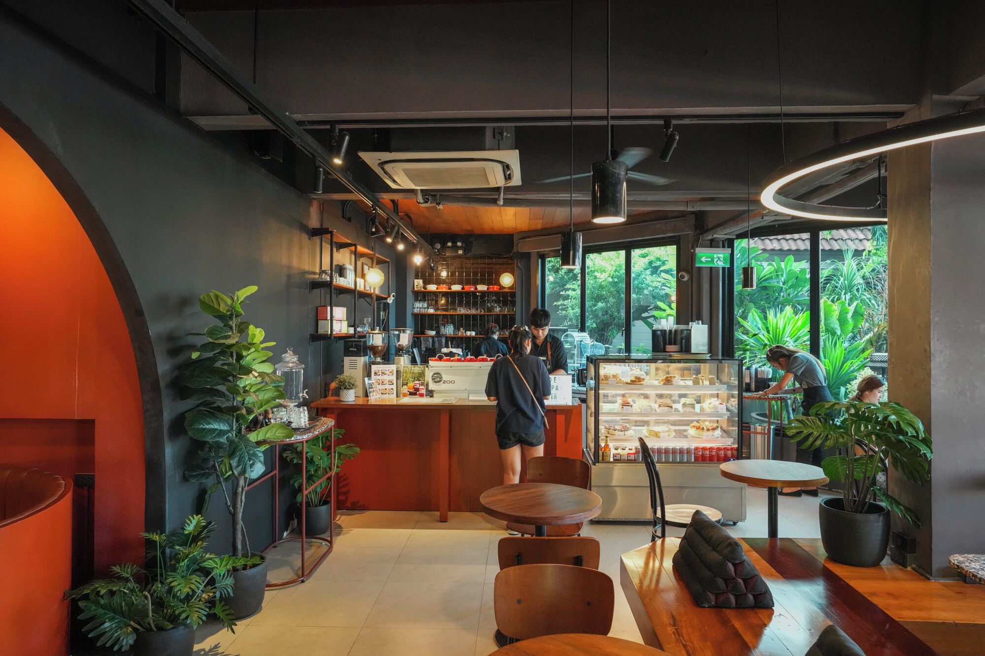 A modern cafe interior with a central counter, seating area, and large windows.
