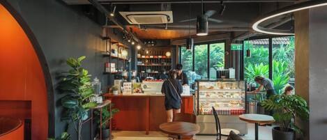 A modern cafe interior with a central counter, seating area, and large windows.
