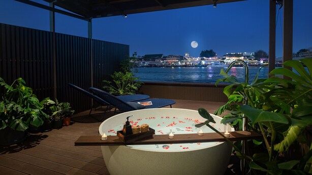 Een dakterras met een jacuzzi, lounge fauteuils en potplanten.