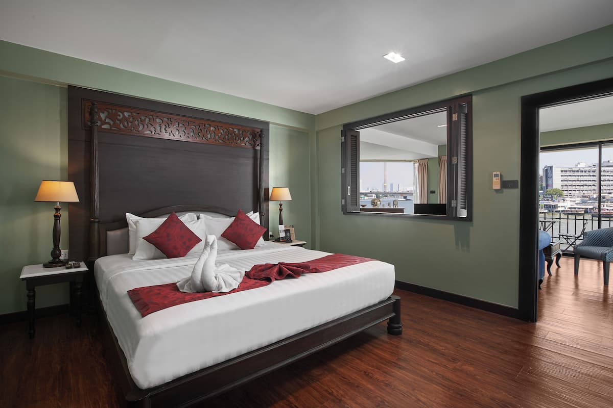 Quarto de hotel com uma cama grande, duas mesas de cabeceira, um criado-mudo, um espelho e vista para a cidade.