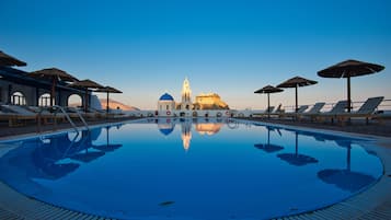 Una piscina al aire libre, sombrillas, sillones reclinables de piscina