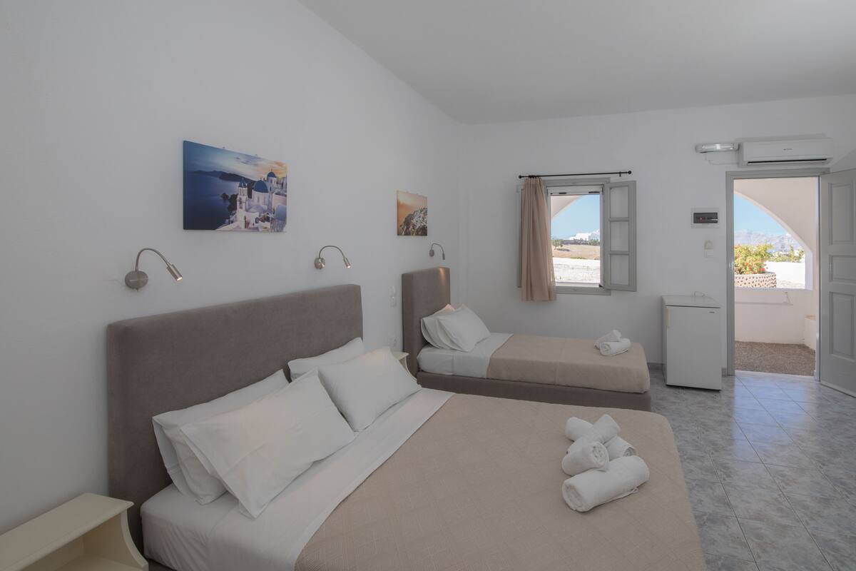 A hotel room with a large bed, a smaller bed, a desk, and a window with a view.