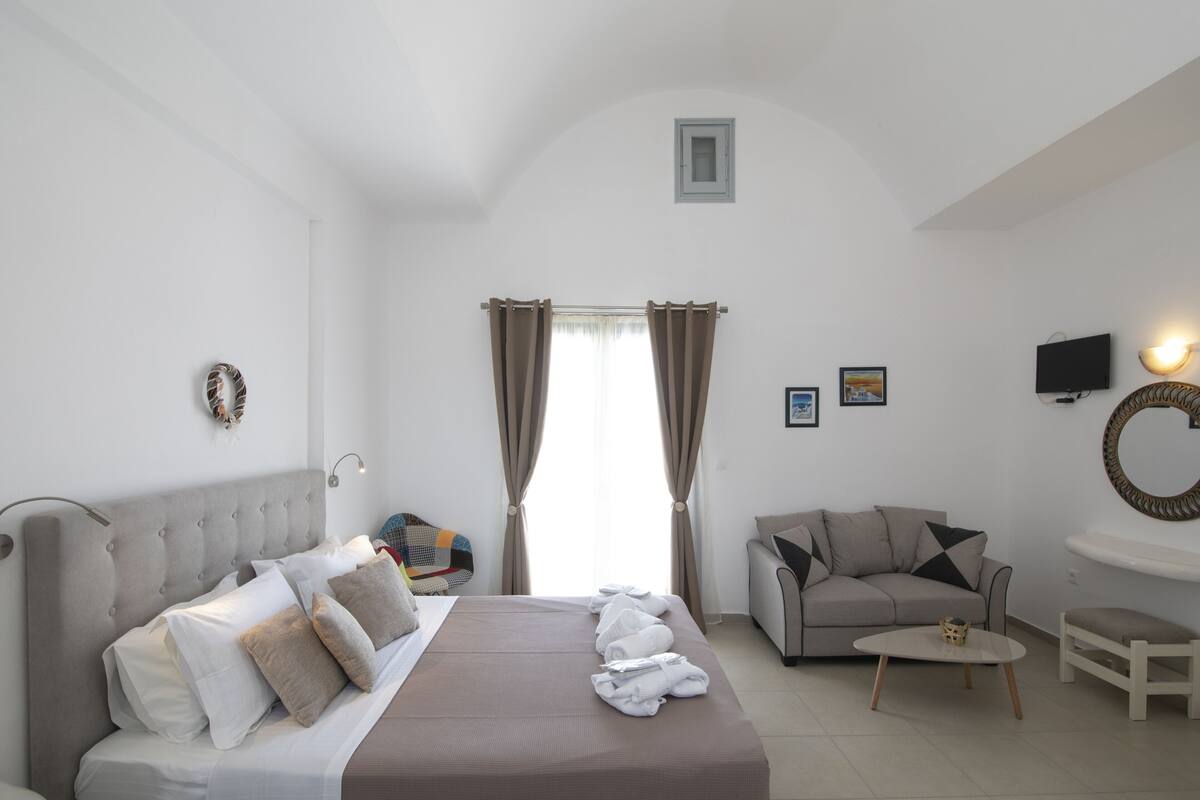A hotel room with a bed, a sofa, a TV, and a small table.