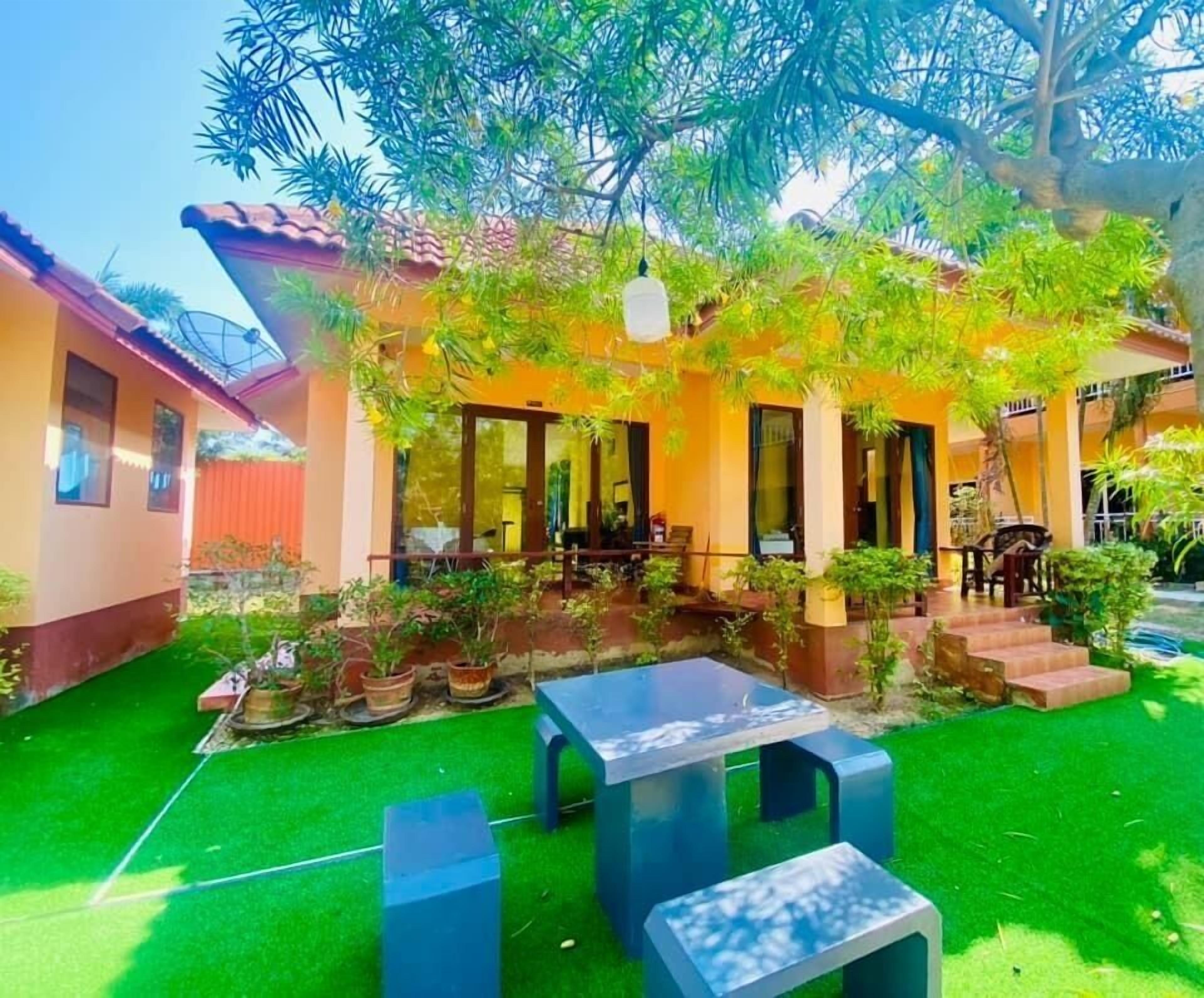 Una casa con patio, mobiliario exterior y plantas en macetas.