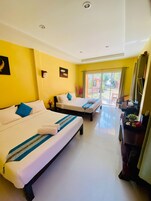 Habitación de hotel con dos camas, un escritorio y vistas al exterior.