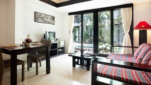 Una sala de estar moderna con comedor, un sofá con cojines a rayas, un televisor y un amplio ventanal con cortinas.