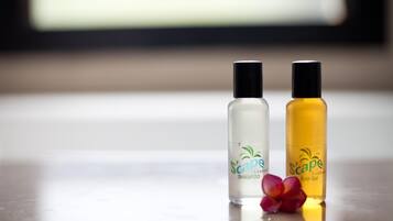 Two bottles of 'Scape' shampoo and bath gel on a reflective surface with a blurred background.