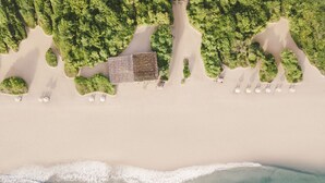 An aerial view of a beach with a row of white umbrellas and a building with a grid-like roof. - Jungle Beach an Uga Experience - Trincomalee (Kuchchaveli)