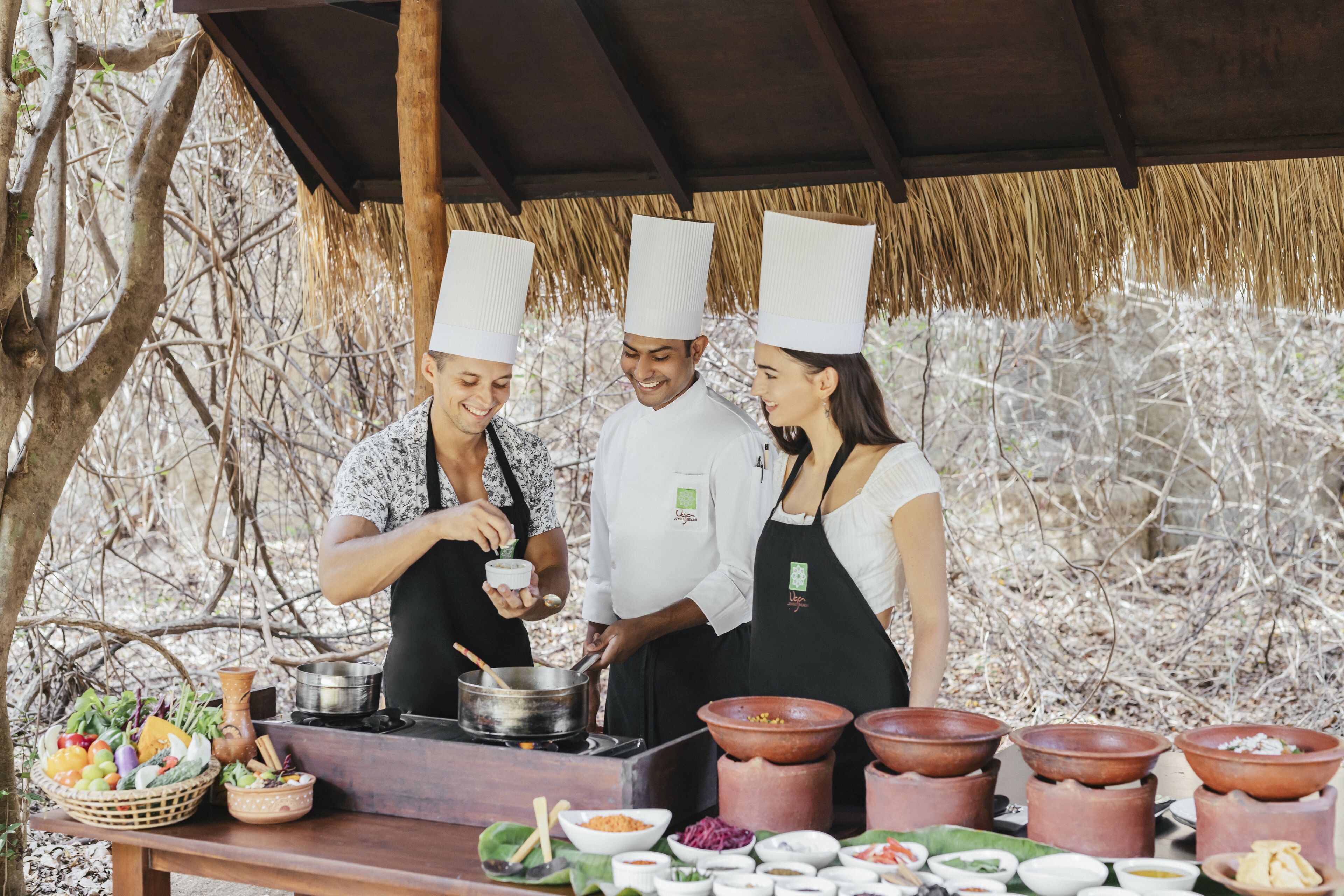 A group of chefs preparing food outdoors with cooking equipment and ingredients visible.