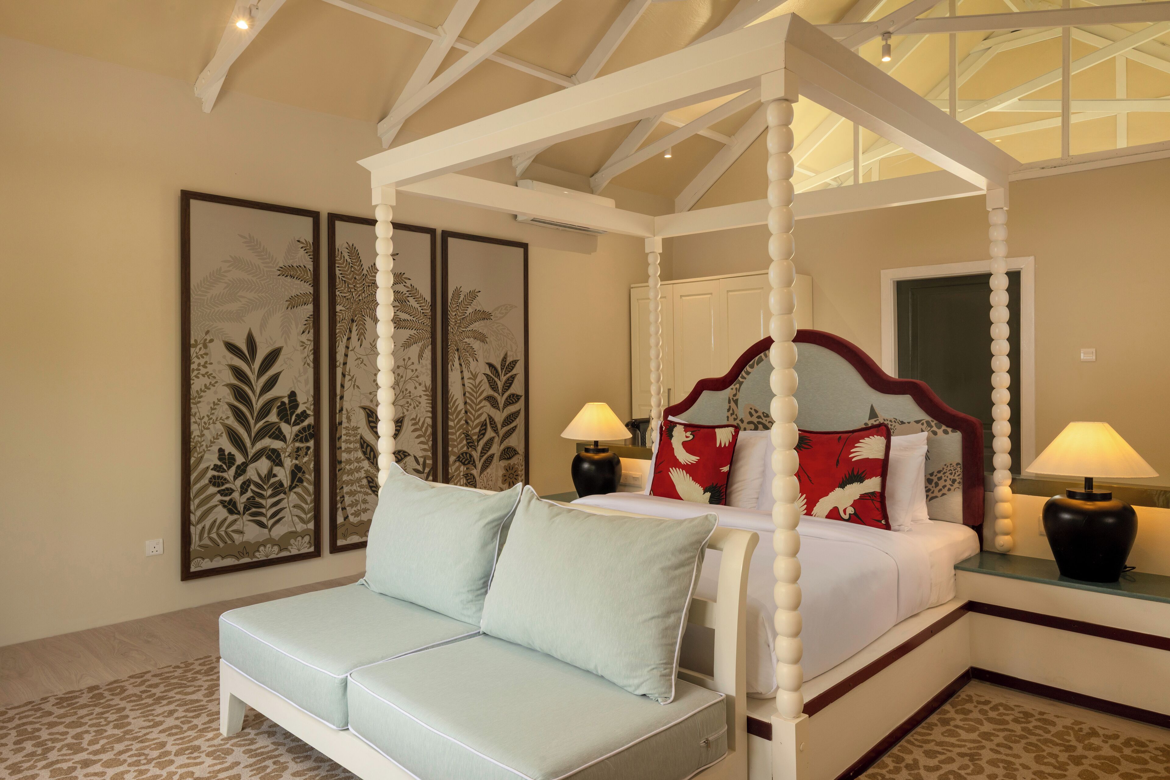 A four-poster bed with a canopy, a light blue sofa, and two bedside lamps.